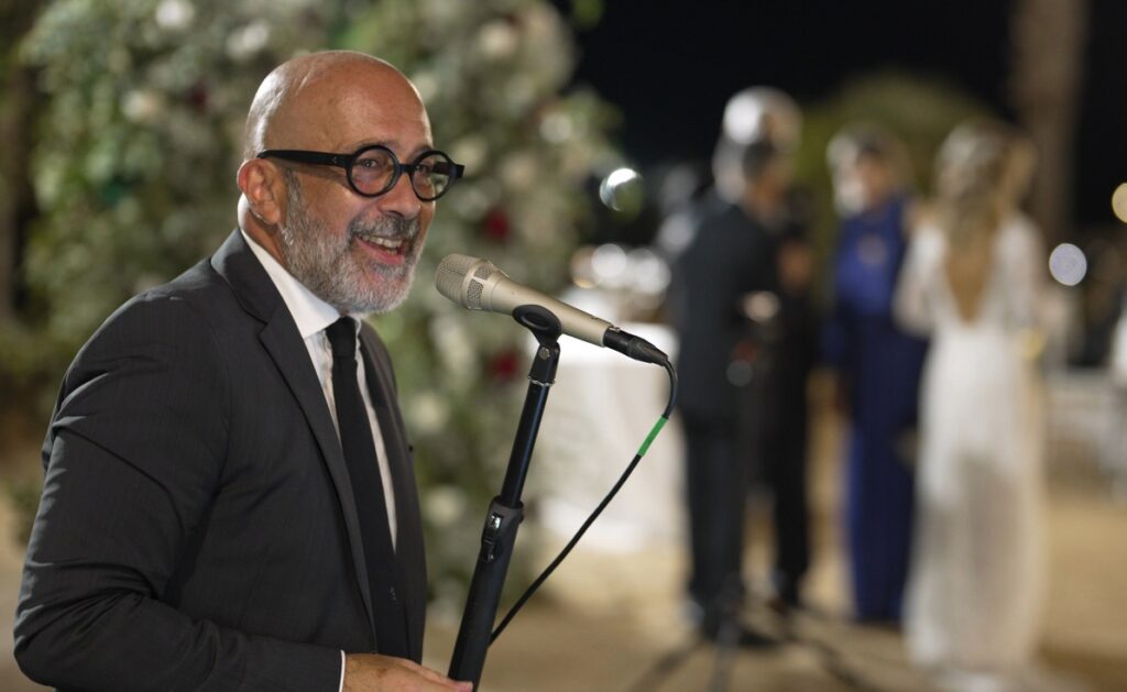 Samaritano canta "Quizas quizas quizas". Cantante in primo piano a sinistra. Sulla destra, sfocati sullo sfondo, la sposa, lo sposo ed un'invitata