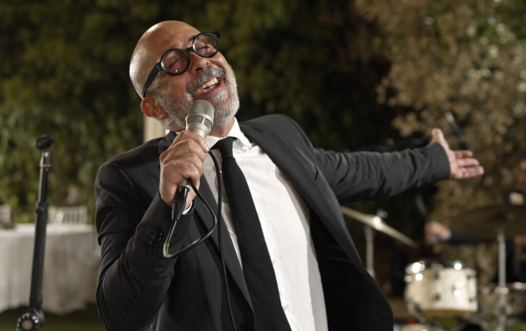 Salvo Samaritano, leader Sarabanda, interpreta Tu si' 'na cosa grande a Costa Ponente di Capo Gallo, Palermo, durante il ricevimento di un matrimonio.