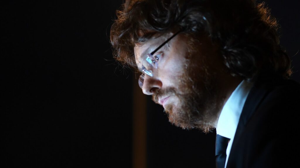 Roberto Mezzatesta, pianista Sarabanda, primissimo piano di profilo su sfondo scuro