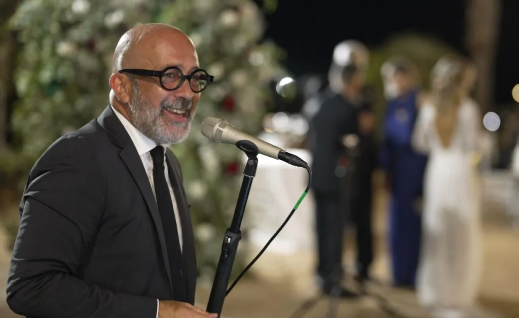 Samaritano canta "Quizas quizas quizas". Cantante in primo piano a sinistra. Sulla destra, sfocati sullo sfondo, la sposa, lo sposo ed un'invitata