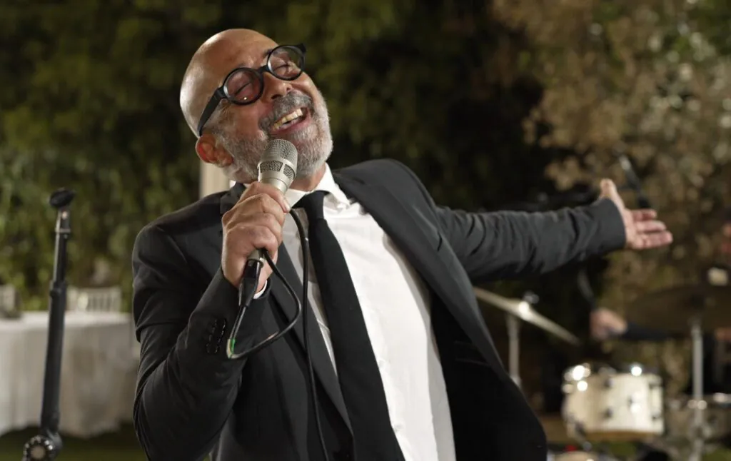 Salvo Samaritano, leader Sarabanda, interpreta Tu si' 'na cosa grande a Costa Ponente di Capo Gallo, Palermo, durante il ricevimento di un matrimonio.