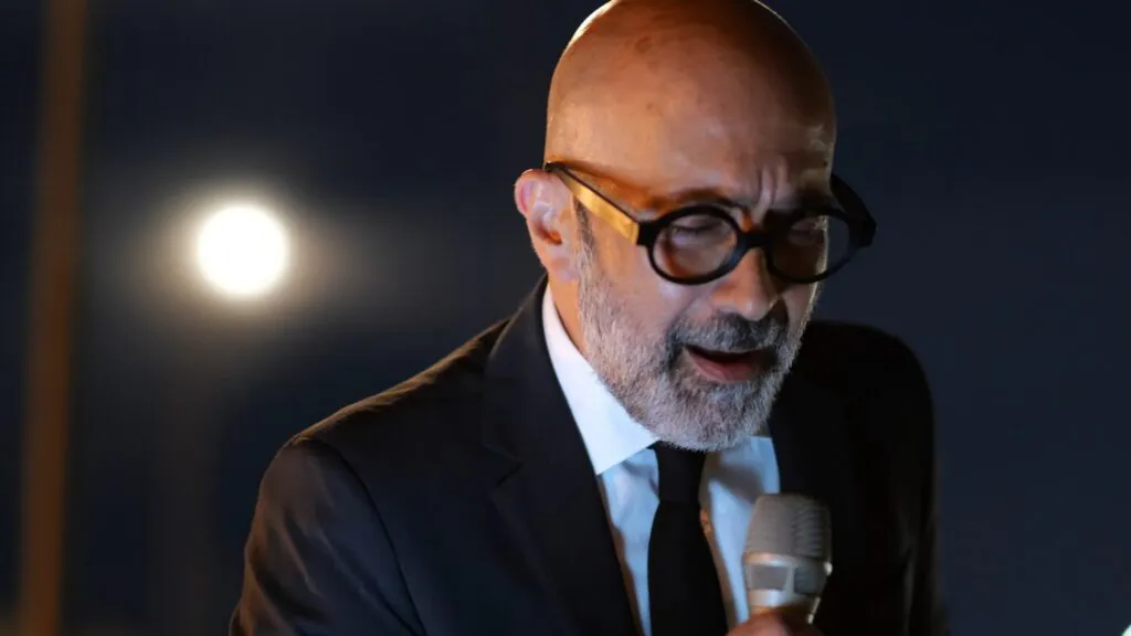 Primissimo piano di Salvo Samaritano che canta "Che cosa c'è" di Gino Paoli. La luna sullo sfondo