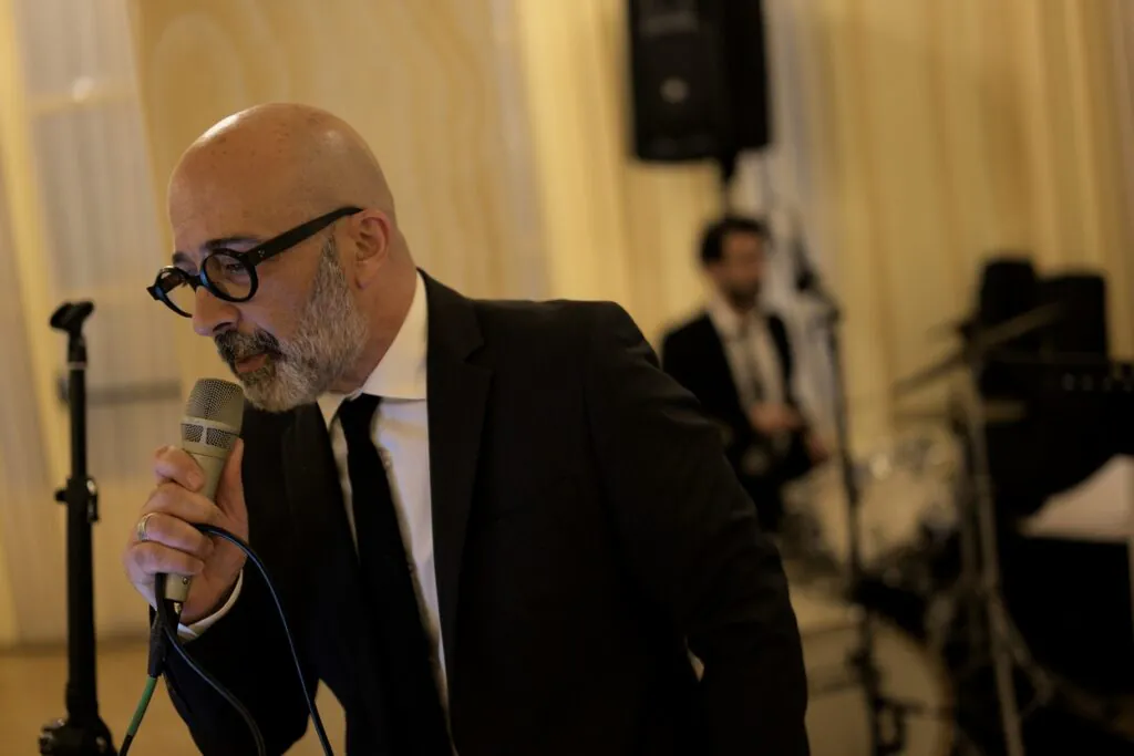 Salvo Samaritano canta a un matrimonio a Villa Igiea (Palermo). Toni gialli della sala. Batterista sullo sfondo